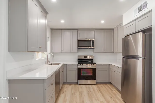 a kitchen with a sink a refrigerator a stove top oven and cabinets
