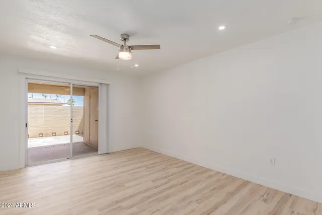 an empty room with wooden floor ceiling fan and windows