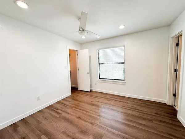 an empty room with wooden floor chandelier and windows