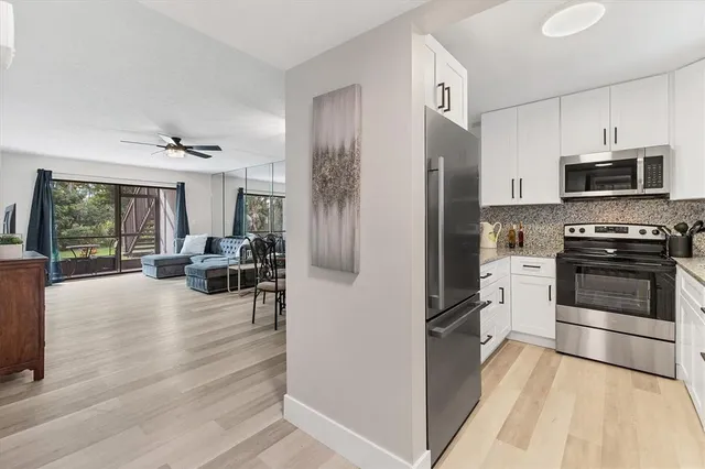 a kitchen with stainless steel appliances a stove a refrigerator cabinets and a dining table