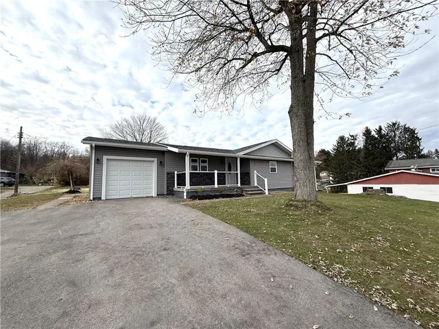 a view of a house with a yard and large tree
