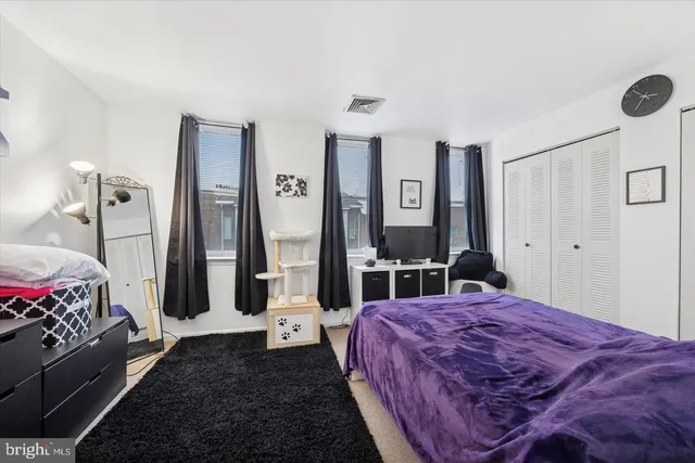 a bedroom with a bed and a large mirror on the dresser