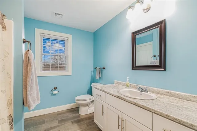 a bathroom with a granite countertop toilet a sink and a mirror