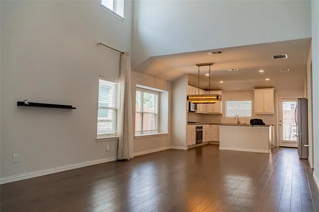 an open kitchen with a refrigerator and wooden floor