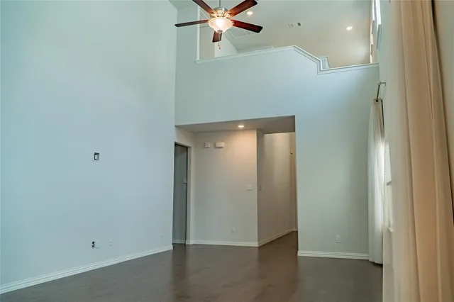 an empty room with wooden floor and fan
