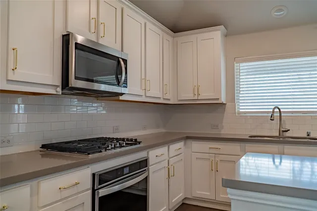 a kitchen with granite countertop white cabinets appliances and a sink
