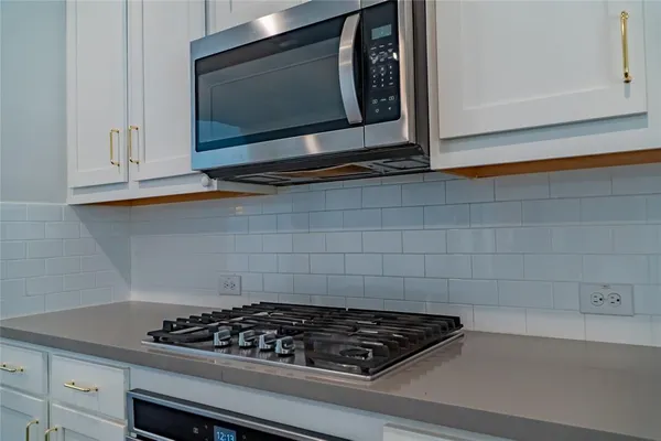 a kitchen with a stove a microwave and cabinets