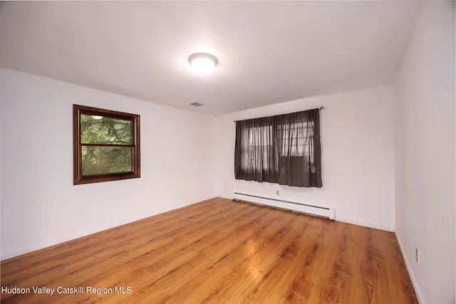 a view of an empty room with wooden floor and window