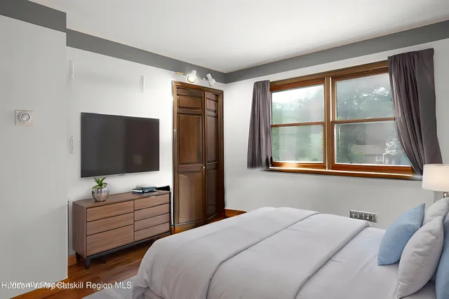 a bedroom with a bed and a flat tv screen on dresser