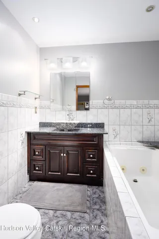 a spacious bathroom with a granite countertop sink mirror and bathtub