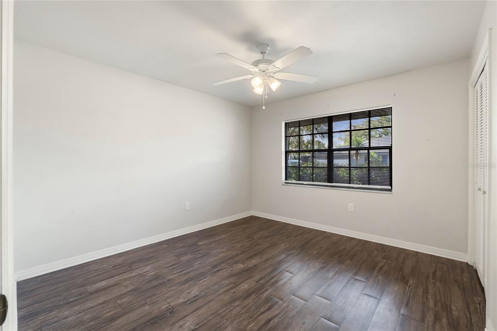 2723 Beacon Street Eustis, FL 32726 - Photo 20 of 42 an empty room with wooden floor chandelier fan and windows