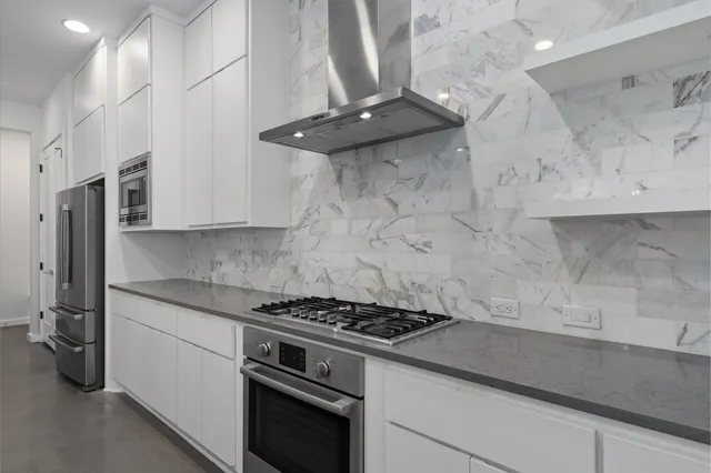 a large kitchen with stainless steel appliances kitchen island a large counter top and wooden floors