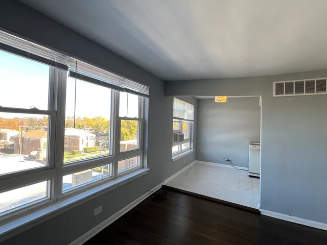 a view of an empty room with a window and wooden floor