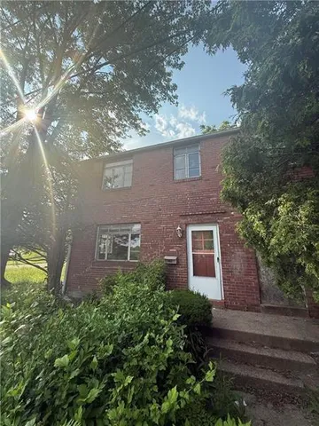 a view of a brick house with a yard and large trees