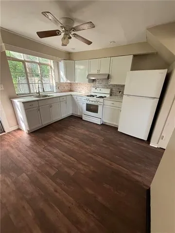 a kitchen with stainless steel appliances a sink a stove a refrigerator cabinets and a large window