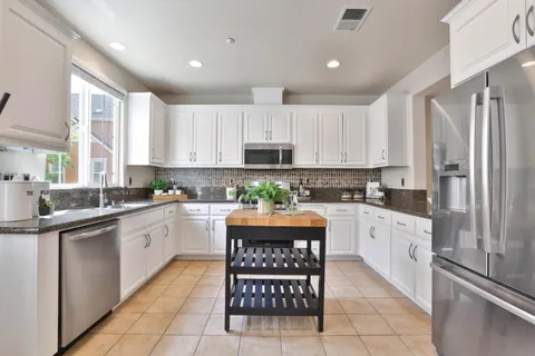 a kitchen with stainless steel appliances granite countertop a refrigerator and a stove top oven