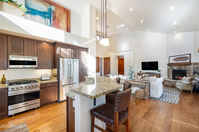 a view of a kitchen with kitchen island granite countertop wooden floor and a view of living room
