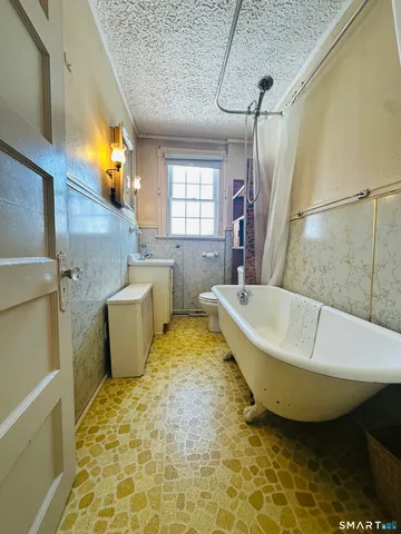 a bathroom with a tub a toilet and a shower