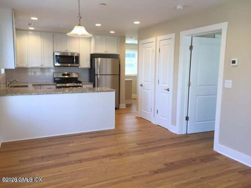 180 Hamilton Avenue, Unit C Greenwich, CT 06830 - Photo 4 of 15 a kitchen with stainless steel appliances granite countertop a refrigerator a stove oven a sink dishwasher and a refrigerator with wooden floor