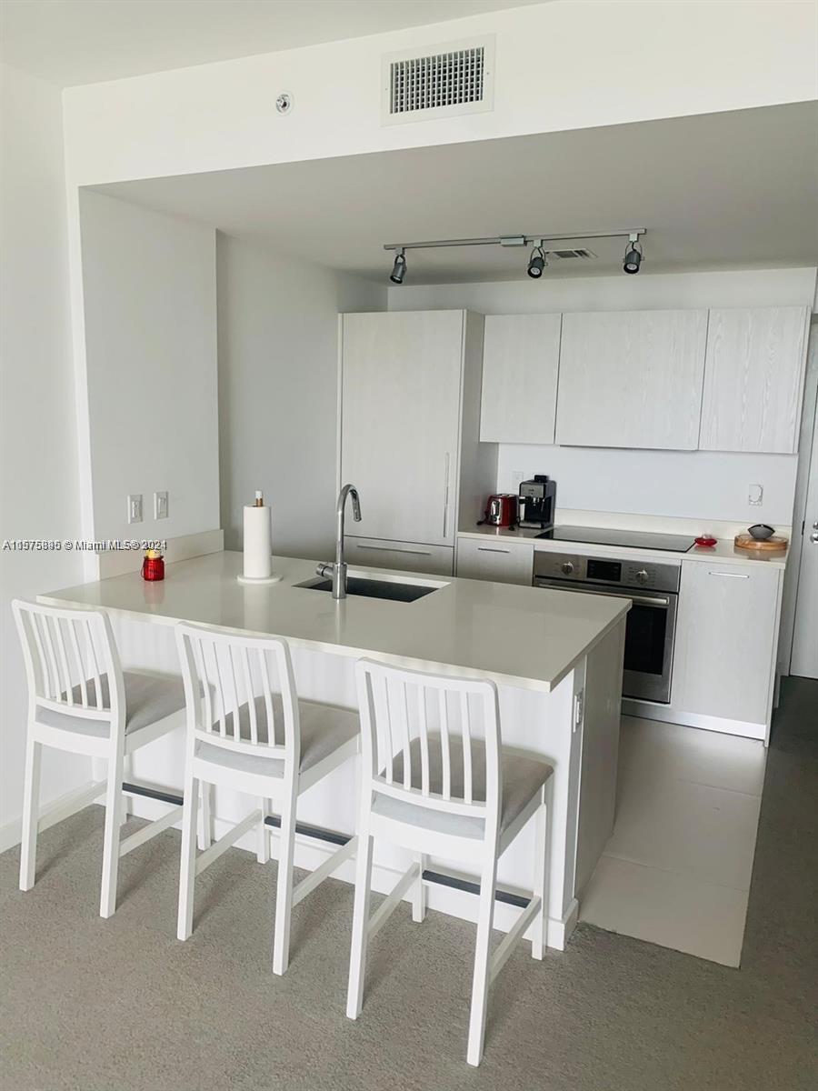 a kitchen with a dining table chairs and white appliances