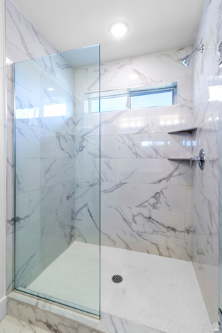 1237 West 500 South, Unit 230 Logan, UT 84321 - Photo 25 of 42 Shower enclosure featuring clear glass panels, marble-look wall tiles, a mosaic tile shower floor, polished chrome fixtures, and built-in shelves