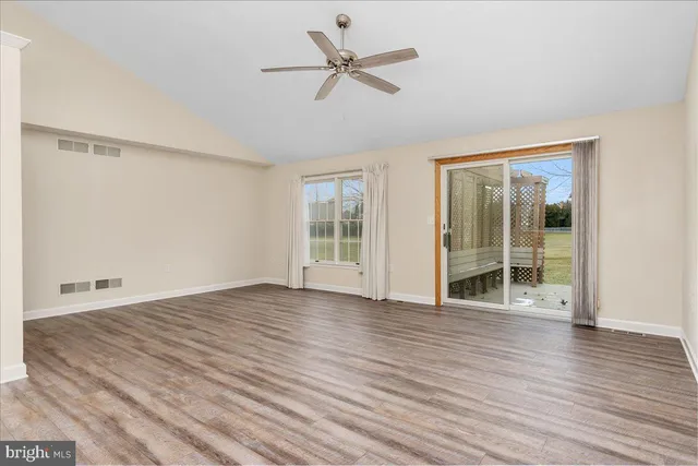 an empty room with wooden floor and a ceiling fan