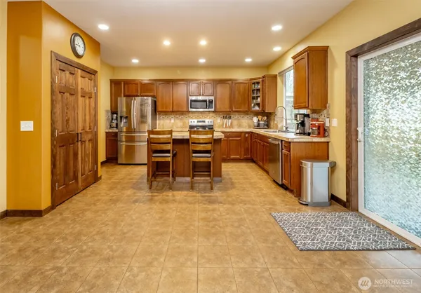 a kitchen with stainless steel appliances granite countertop a sink a stove a refrigerator cabinets and chairs