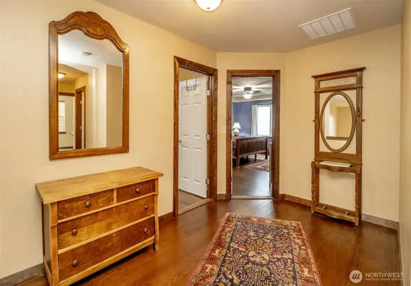 a bedroom with a bed and a dresser with wooden floor