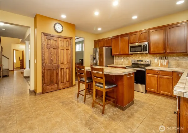 a large kitchen with stainless steel appliances kitchen island granite countertop a refrigerator and cabinets
