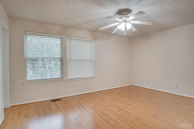 a view of an empty room with a window and a chandelier fan