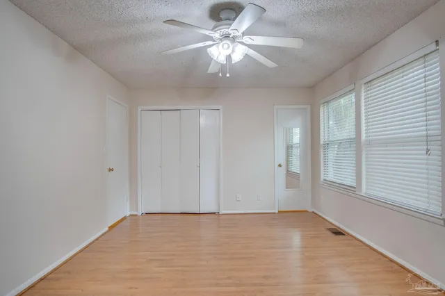 a view of an empty room with window and chandelier fan