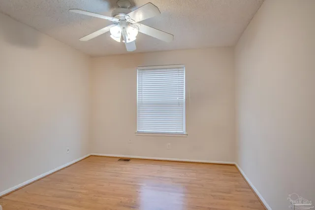 an empty room with a window and a fan