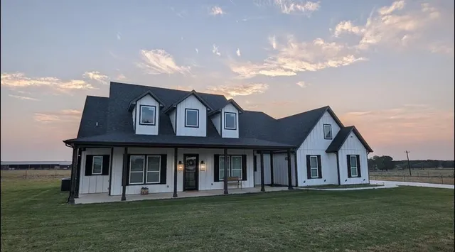 a view of a white house with a big yard and large trees