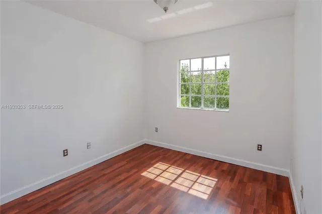a view of an empty room with wooden floor and closet