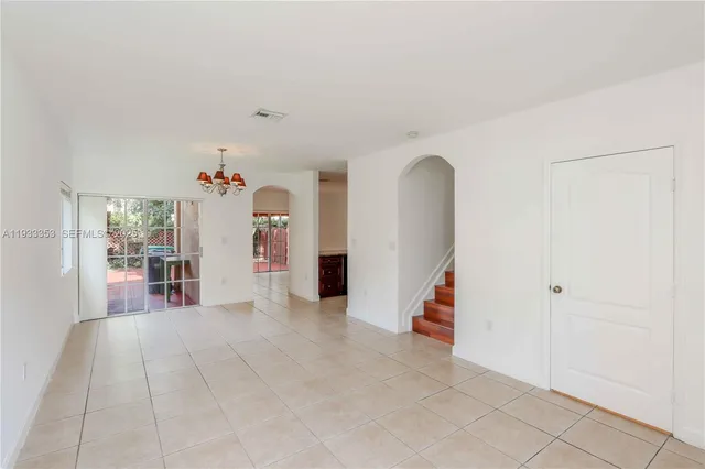 an empty room with a chandelier fan and wooden floor