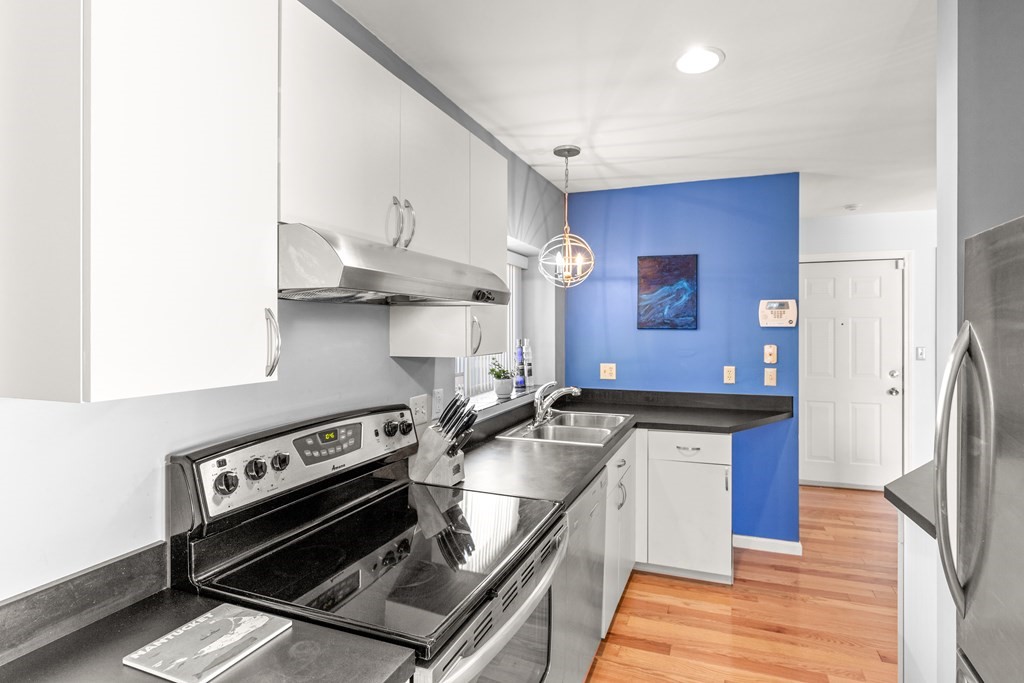 4873 Washington Street, Unit 1 Boston, MA 02132 - Photo 11 of 25 a kitchen with stainless steel appliances granite countertop a stove a sink and a refrigerator