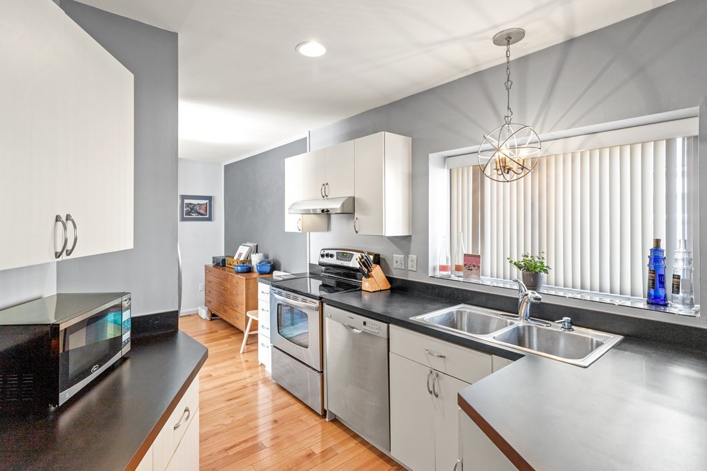 4873 Washington Street, Unit 1 Boston, MA 02132 - Photo 12 of 25 a kitchen with stainless steel appliances a sink stove and cabinets