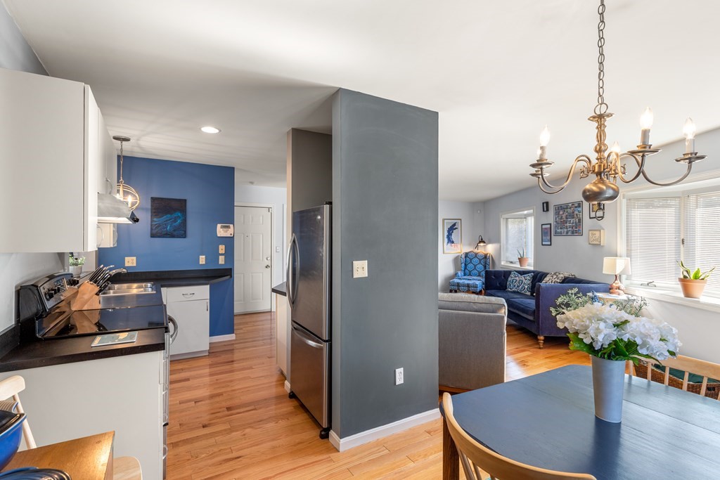 4873 Washington Street, Unit 1 Boston, MA 02132 - Photo 10 of 25 a kitchen with stainless steel appliances granite countertop a refrigerator a sink dishwasher a stove and a dining table with wooden floor