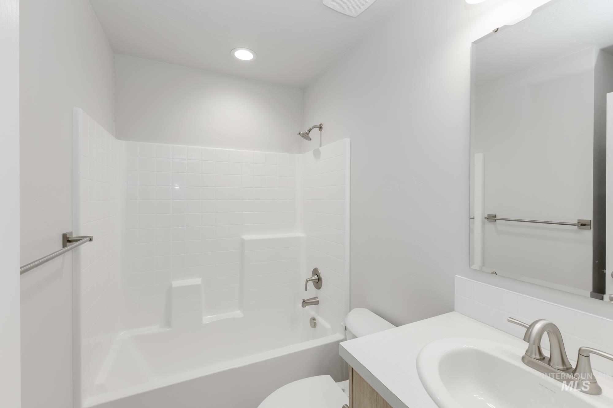 13337 Scrape Street Caldwell, ID 83607 - Photo 11 of 19 White bathtub with integrated shower, vanity with an oval sink, and a framed mirror