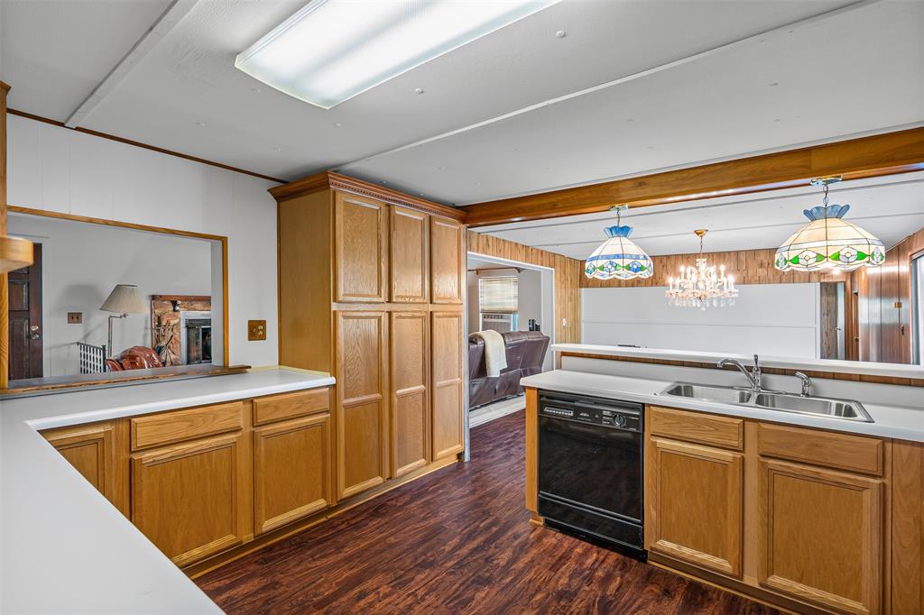 3667 Oak Circle Weatherford, TX 76088 - Photo 20 of 35 Kitchen featuring wood walls, a chandelier, decorative light fixtures, brown cabinets, and black dishwasher