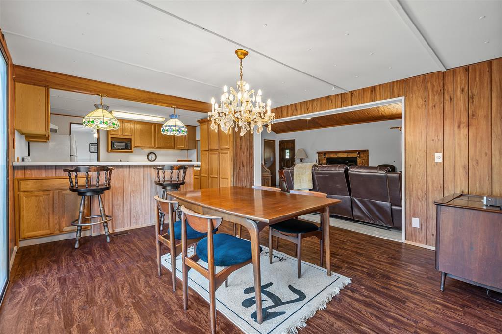 3667 Oak Circle Weatherford, TX 76088 - Photo 22 of 35 Dining area with wood walls, dark wood-style flooring, a chandelier, and a fireplace