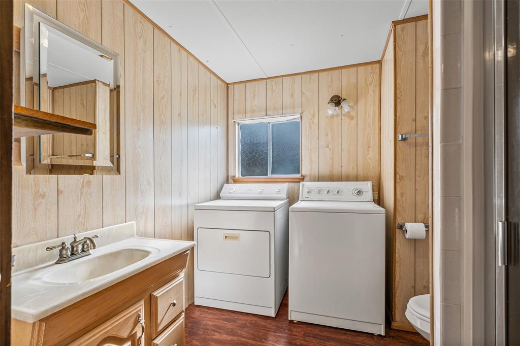 3667 Oak Circle Weatherford, TX 76088 - Photo 24 of 35 Laundry area with dark wood-type flooring, wooden walls, and washing machine and dryer