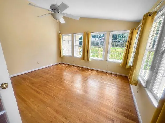a view of an empty room with a window and wooden floor