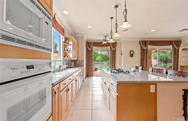 a large kitchen with kitchen island a large counter top a sink a stove and a chandelier
