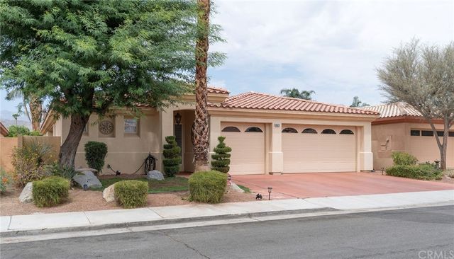 a front view of a house with a yard and potted plants