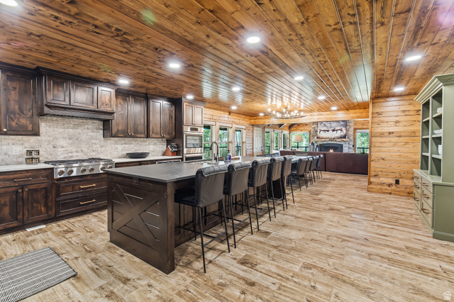 2031 South Quakie Road Koosharem, UT 84744 - Photo 11 of 33 Spacious kitchen and dining area featuring a wood plank ceiling, wood-finish flooring, custom dark wood cabinetry, a large kitchen island with counter seating, and a stone backsplash