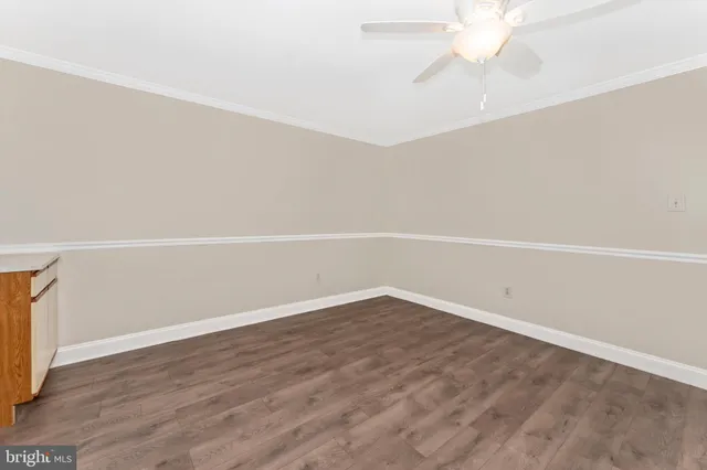 an empty room with wooden floor and fan