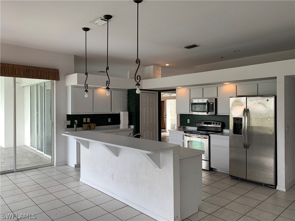 212 Danby Road Lehigh Acres, FL 33936 - Photo 5 of 21 a kitchen with stainless steel appliances a refrigerator sink and microwave