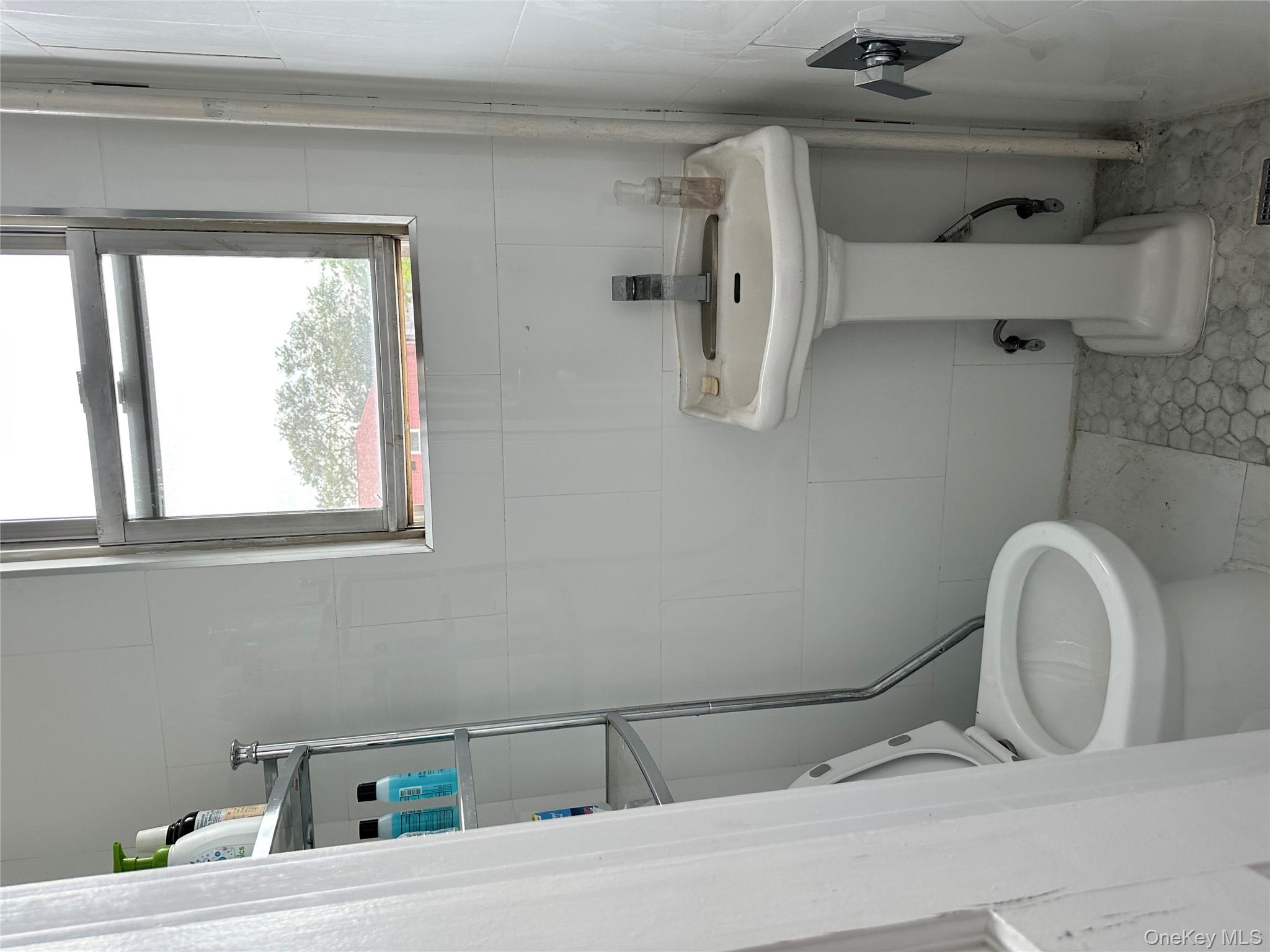 77-02 164th Street, Unit 2 Queens, NY 11366 - Photo 13 of 17 a bathroom with a sink a toilet and a mirror