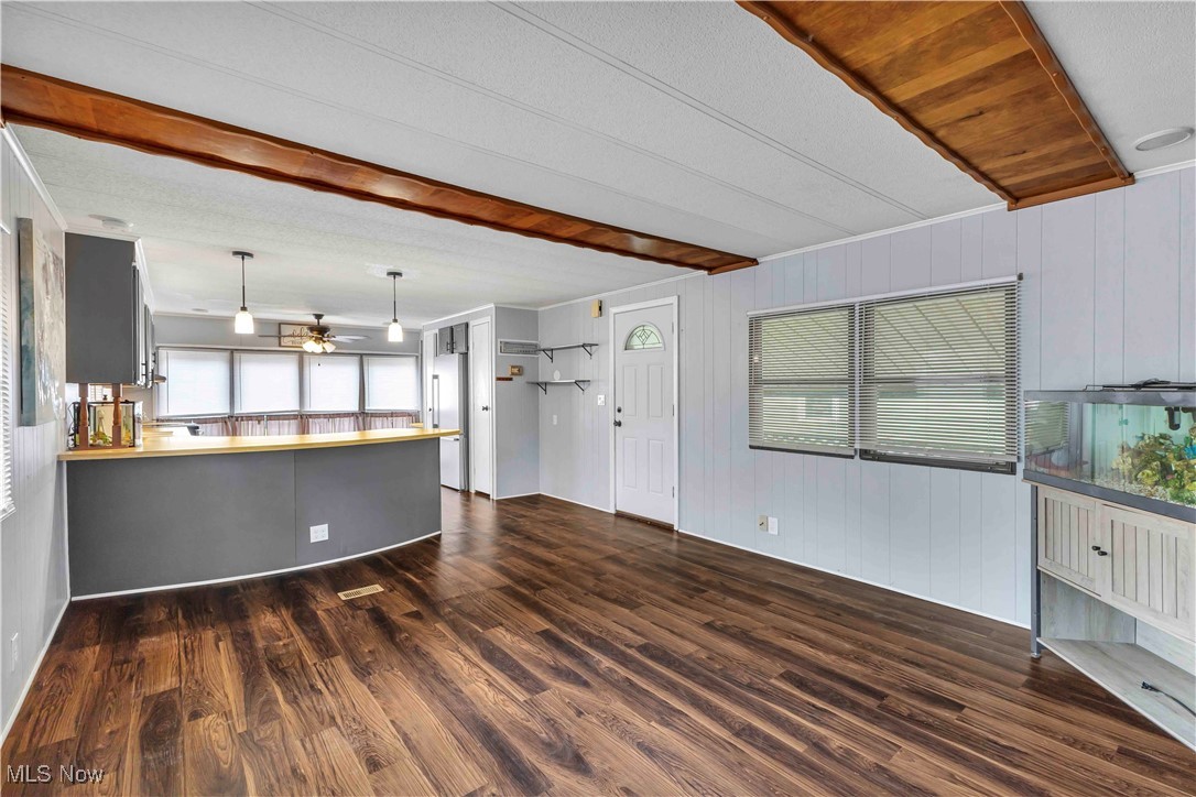35157 Center Ridge Road, Unit 120 North Ridgeville, OH 44039 - Photo 9 of 25 Unfurnished living room featuring dark wood-style flooring, wood walls, and a ceiling fan